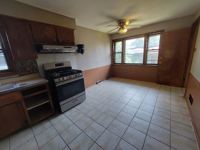 kitchen featuring light tile patterned floors, backsplash, ceiling fan, stainless steel gas stove, and dark brown cabinetry