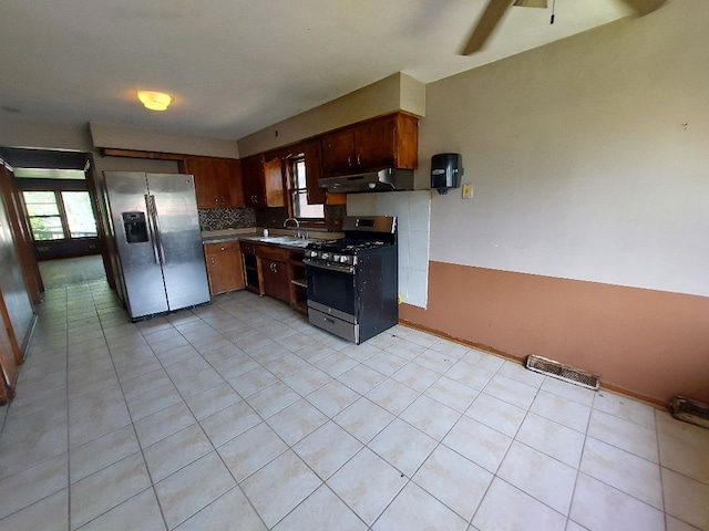 kitchen featuring tasteful backsplash, under cabinet range hood, visible vents, stainless steel appliances, and a sink