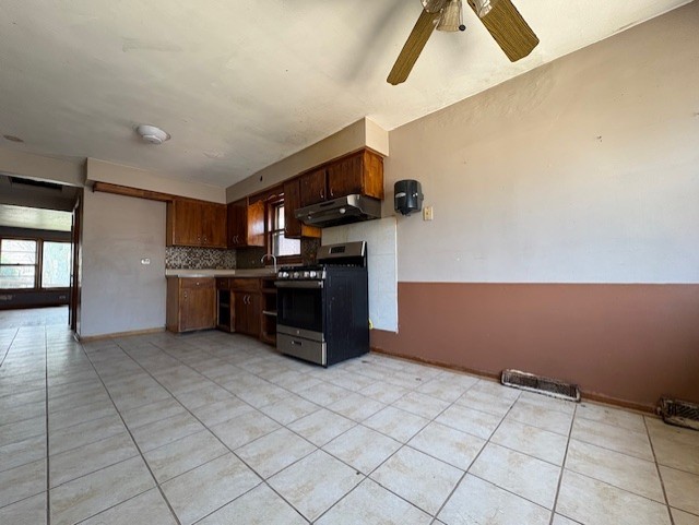 10809 S Mackinaw Ave, Chicago, IL 60617 - kitchen with under cabinet range hood, light tile patterned flooring, decorative backsplash, and stainless steel gas range oven