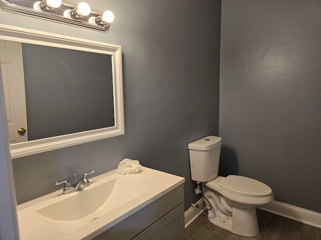 bathroom with vanity, toilet, and hardwood / wood-style floors