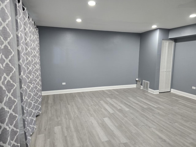 finished below grade area featuring recessed lighting, visible vents, baseboards, and wood finished floors