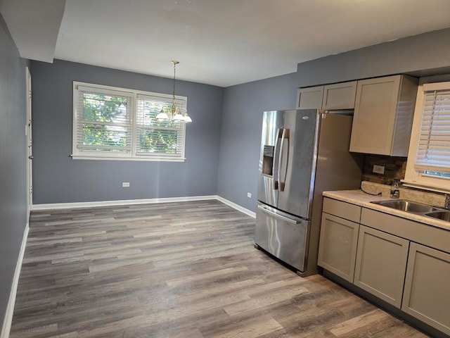 kitchen featuring an inviting chandelier, stainless steel fridge, decorative light fixtures, light hardwood / wood-style floors, and sink