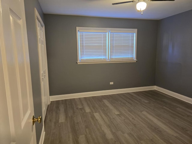spare room with baseboards, ceiling fan, and dark wood finished floors