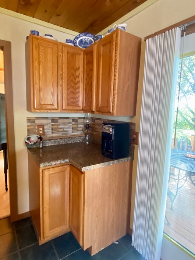 kitchen with dark tile patterned floors, backsplash, and dark stone counters