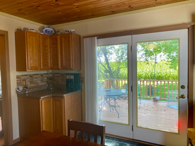 kitchen featuring dark tile patterned floors, wooden ceiling, stone counters, and tasteful backsplash