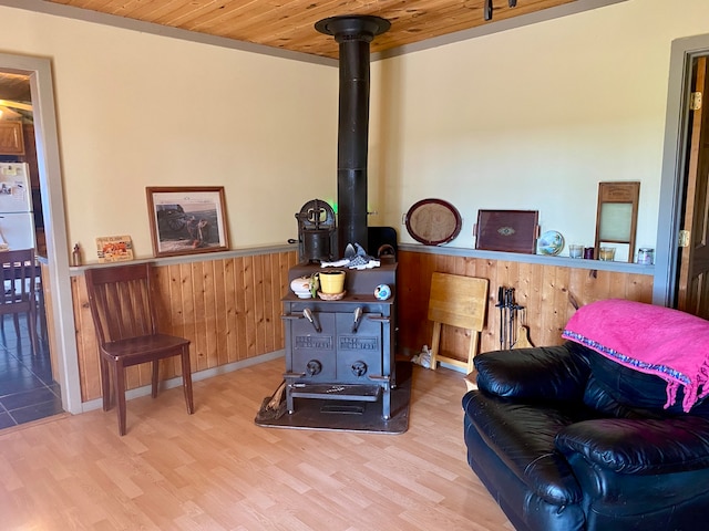 living area featuring wooden ceiling, hardwood / wood-style floors, a wood stove, and wooden walls