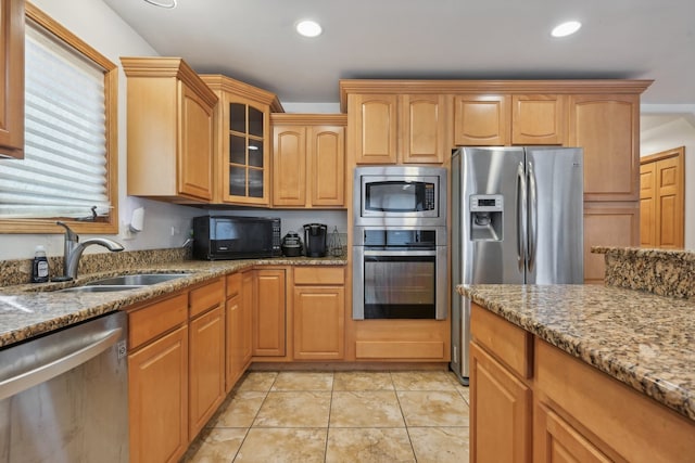 kitchen with appliances with stainless steel finishes, light tile patterned floors, light stone countertops, and sink