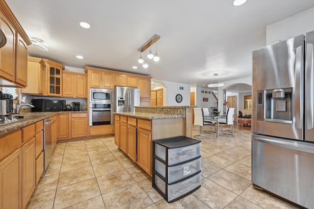 kitchen with hanging light fixtures, light tile patterned floors, a center island, stainless steel appliances, and stone countertops