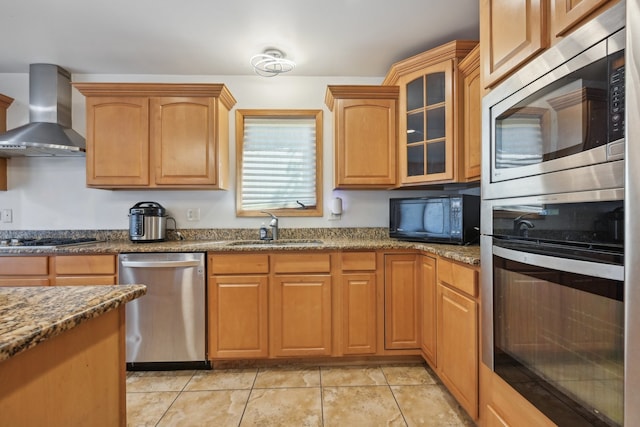 kitchen with stone counters, appliances with stainless steel finishes, sink, wall chimney exhaust hood, and light tile patterned flooring