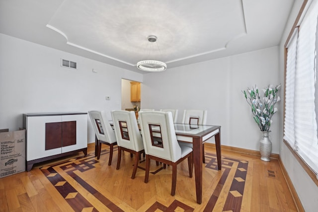 dining room with light hardwood / wood-style flooring and an inviting chandelier