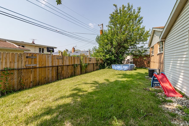 view of yard featuring a covered pool and central air condition unit