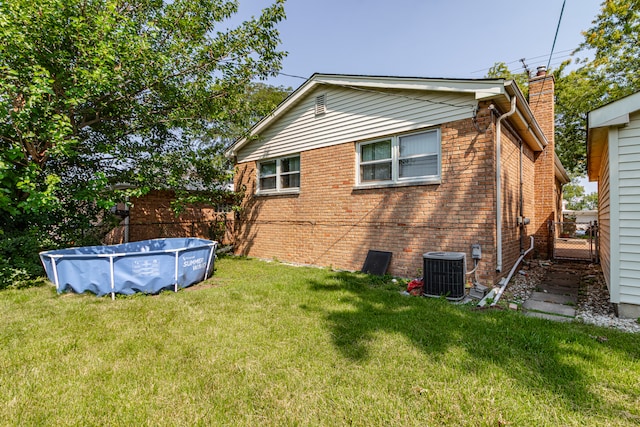 rear view of house with a covered pool, a yard, and cooling unit