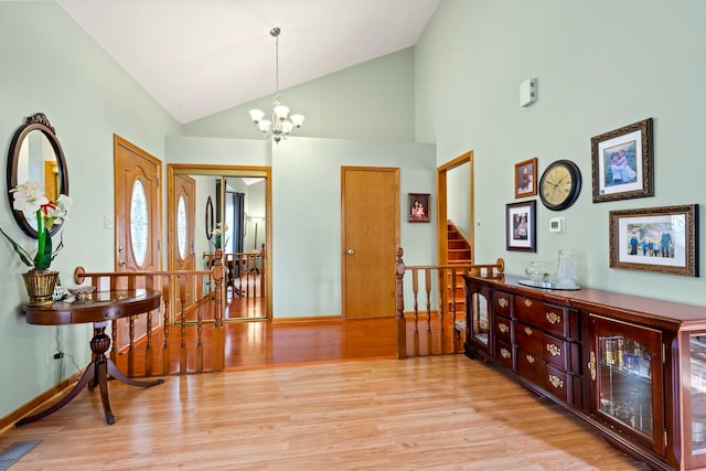 interior space featuring an inviting chandelier, high vaulted ceiling, and light hardwood / wood-style flooring