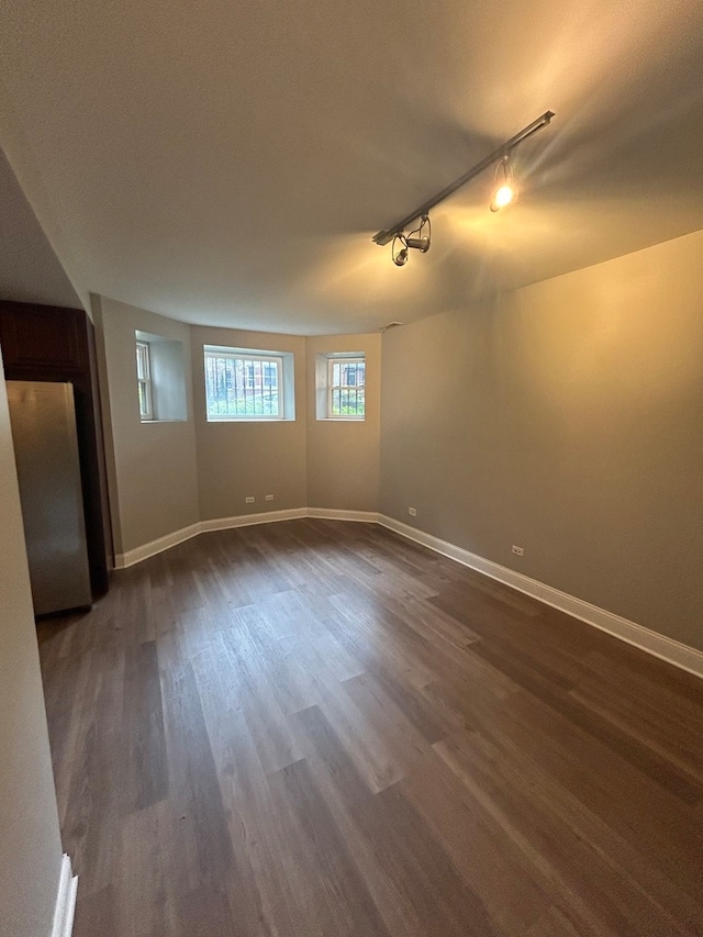 empty room featuring rail lighting and dark wood-type flooring