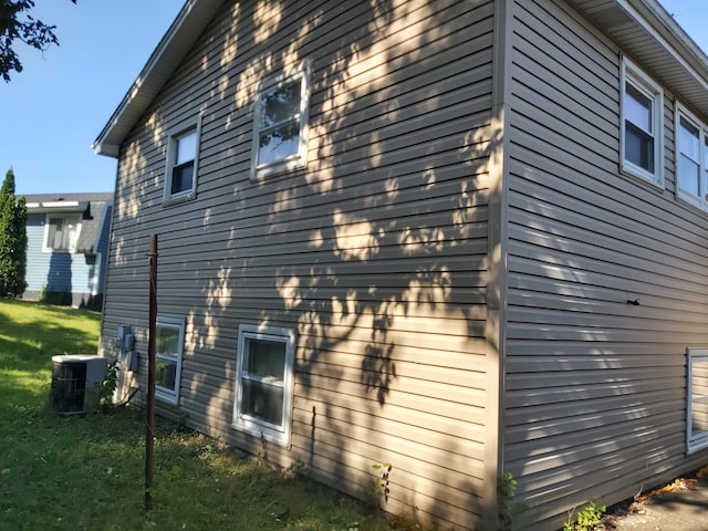 view of property exterior with cooling unit and a lawn