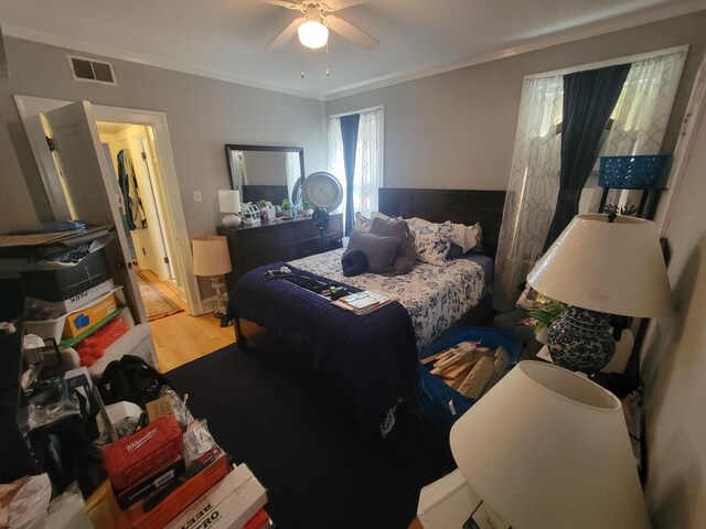 bedroom with crown molding, multiple windows, hardwood / wood-style floors, and ceiling fan