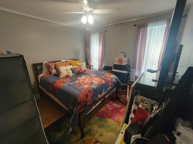 bedroom featuring ornamental molding, multiple windows, hardwood / wood-style floors, and ceiling fan