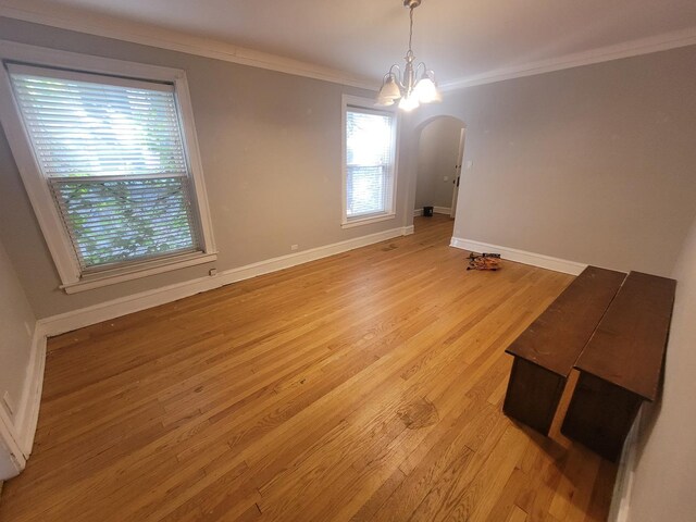 spare room with crown molding, a notable chandelier, and light hardwood / wood-style floors