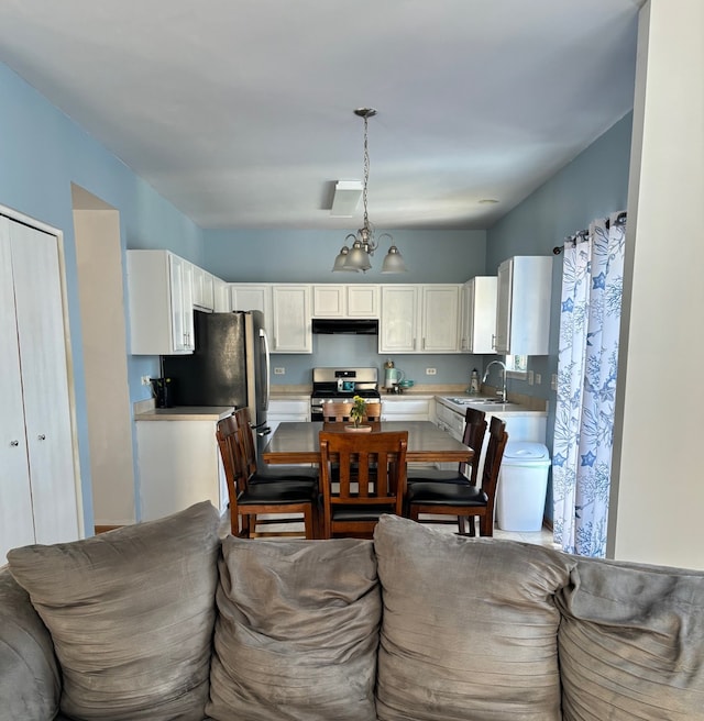 interior space featuring a chandelier, sink, white cabinetry, hanging light fixtures, and stainless steel appliances