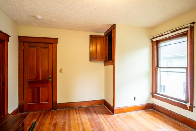 empty room with a textured ceiling and light hardwood / wood-style floors