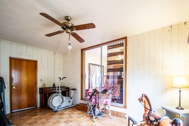 misc room featuring wood walls, parquet floors, and ceiling fan