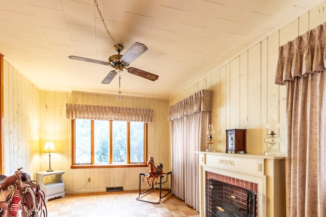 interior space featuring ceiling fan, a brick fireplace, and wooden walls