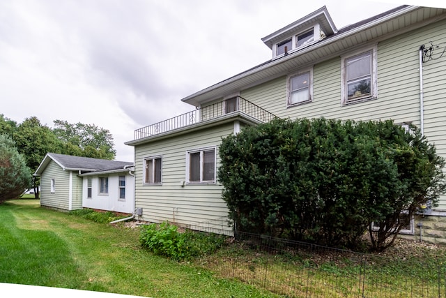 back of house with a balcony and a lawn