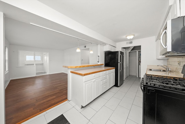 kitchen with stainless steel appliances, light hardwood / wood-style floors, white cabinetry, sink, and butcher block counters