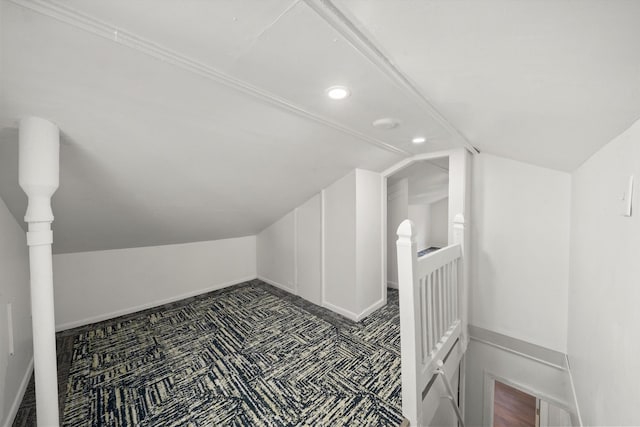 additional living space featuring lofted ceiling and dark colored carpet