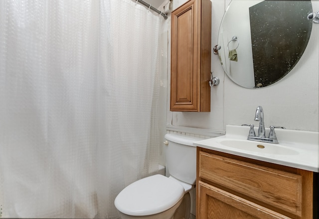 bathroom with curtained shower, vanity, and toilet