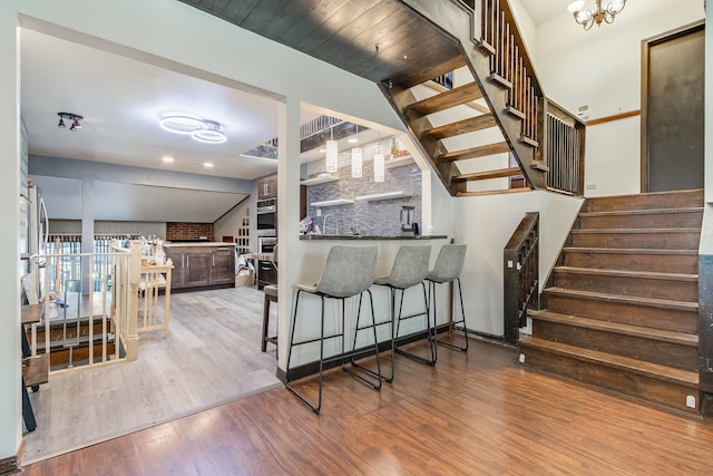 staircase with wood-type flooring and bar