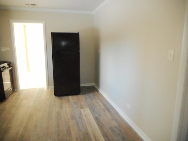 kitchen featuring black refrigerator, light hardwood / wood-style flooring, crown molding, and white gas stove