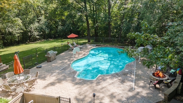 view of swimming pool featuring a yard, a patio area, and an outdoor fire pit