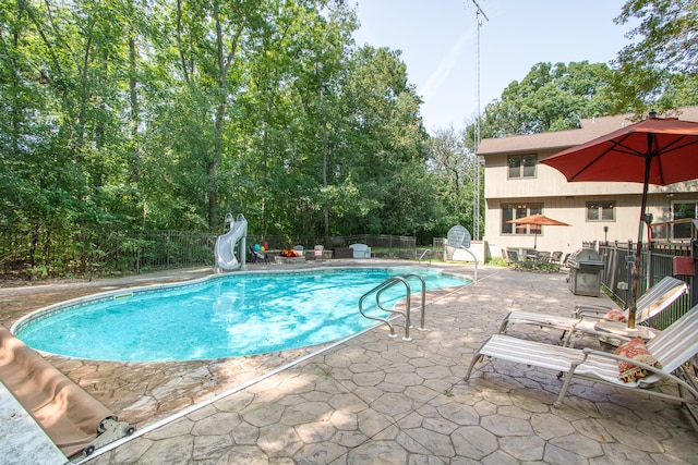 view of swimming pool featuring a water slide and a patio area