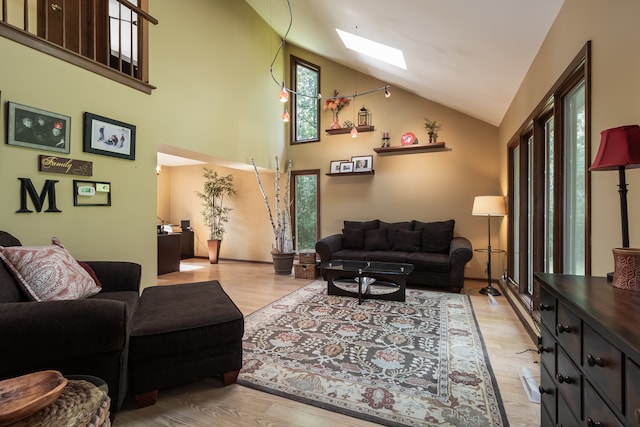 living room with plenty of natural light, high vaulted ceiling, and a skylight