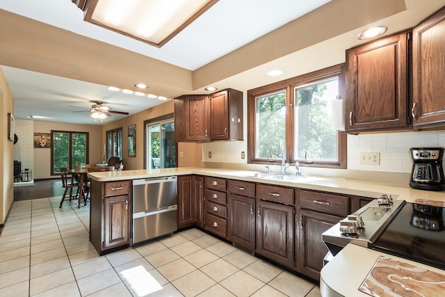 kitchen with a brick fireplace, kitchen peninsula, sink, ceiling fan, and light tile patterned flooring