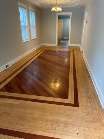 empty room with an inviting chandelier and hardwood / wood-style floors