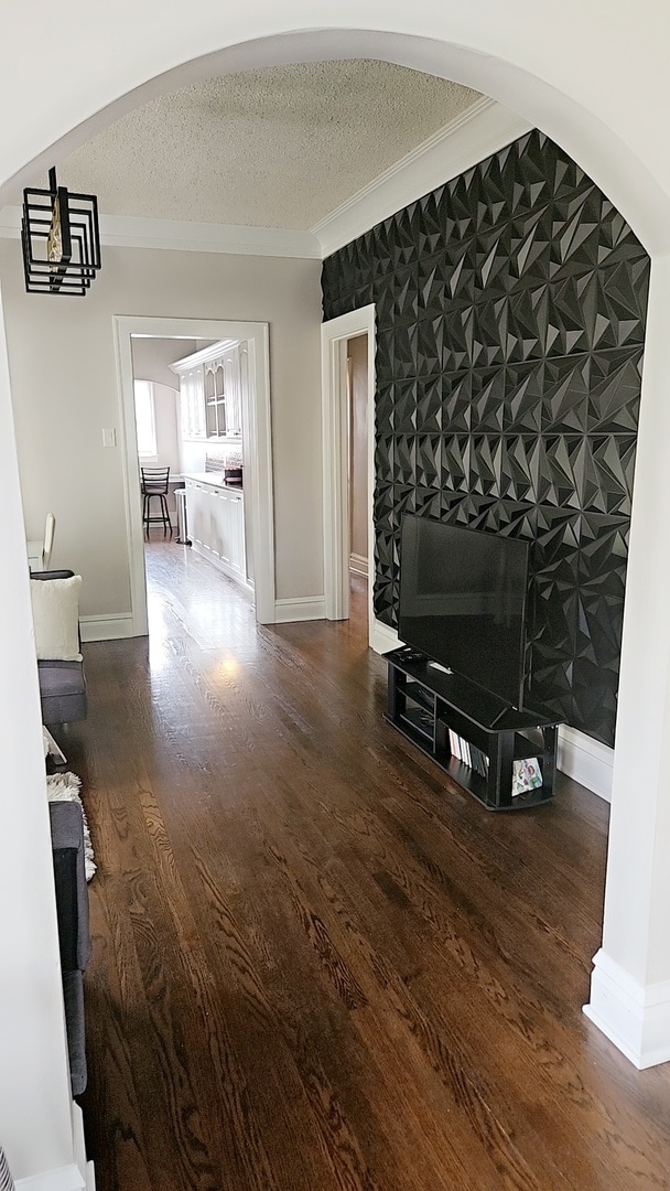 hallway featuring ornamental molding, hardwood / wood-style floors, and a textured ceiling