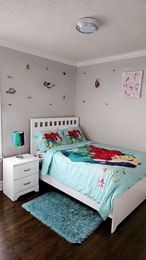 bedroom with crown molding, dark wood-type flooring, and a textured ceiling