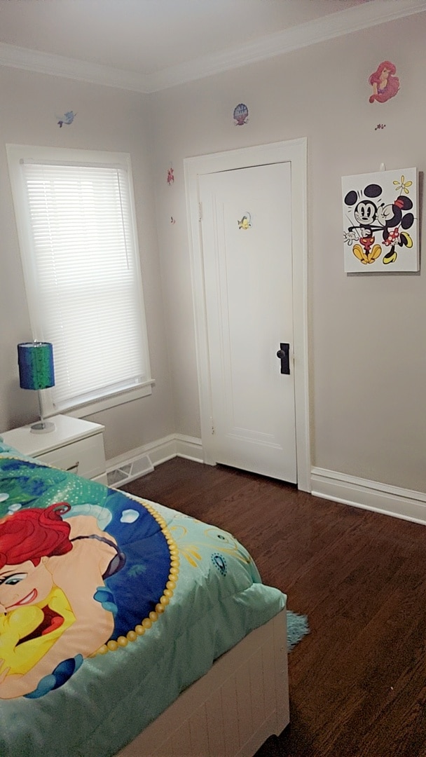 bedroom with crown molding and dark wood-type flooring