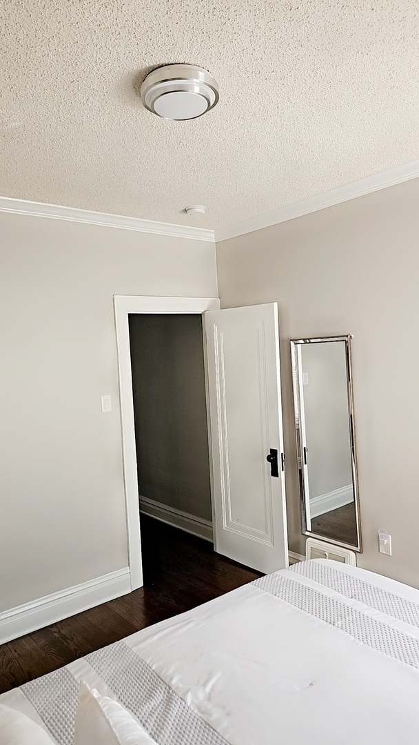 unfurnished bedroom with dark hardwood / wood-style floors, ornamental molding, and a textured ceiling