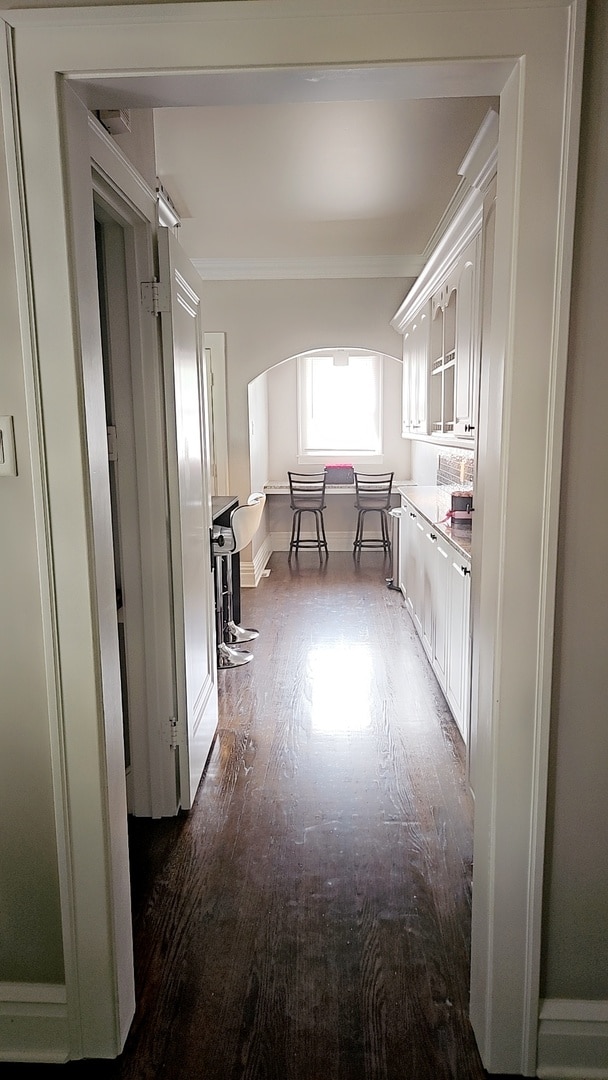 hallway featuring dark wood-type flooring and crown molding