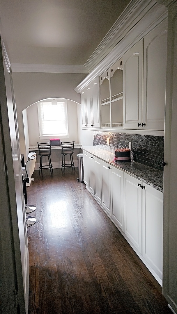 kitchen featuring backsplash, dark hardwood / wood-style flooring, light stone counters, and white cabinetry