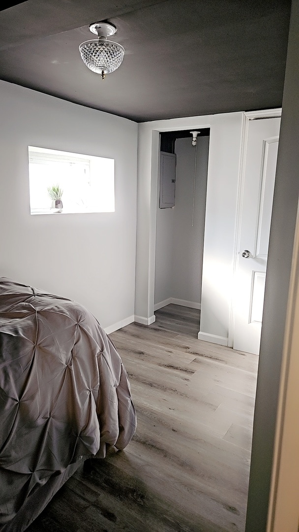 bedroom featuring electric panel and light hardwood / wood-style floors