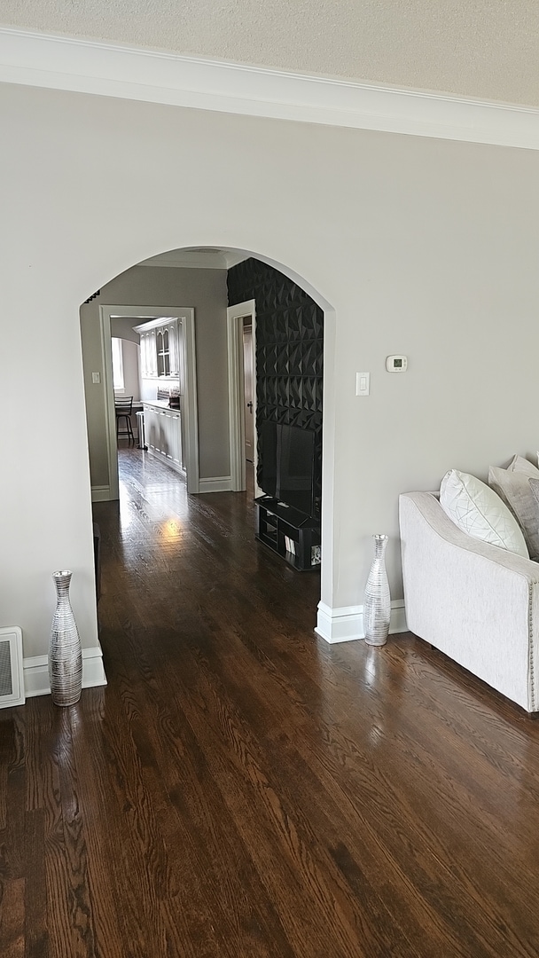 interior space featuring a textured ceiling, crown molding, and dark hardwood / wood-style flooring