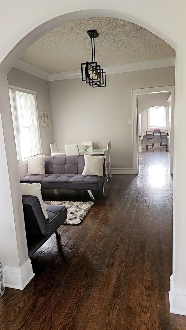 living room with crown molding, a chandelier, hardwood / wood-style flooring, and a textured ceiling