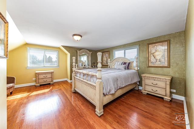 bedroom featuring multiple windows, lofted ceiling, and hardwood / wood-style floors