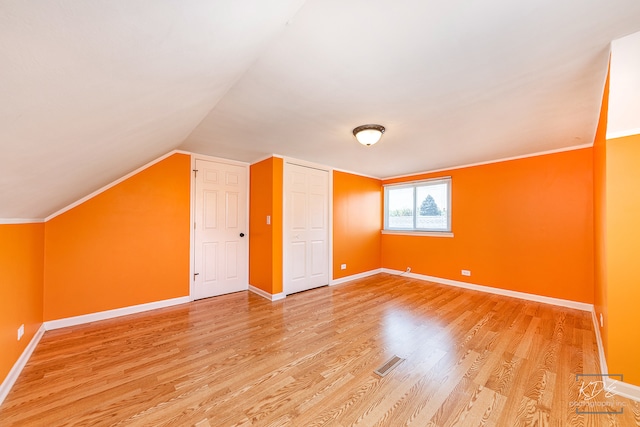 additional living space with wood-type flooring and vaulted ceiling