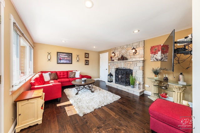 living room with a stone fireplace and dark hardwood / wood-style flooring