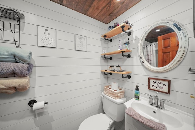 bathroom with toilet, wood ceiling, sink, and wooden walls